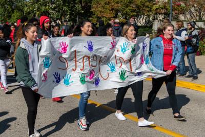 Students in the organization Mi Gente walk in the Homecoming Parade.